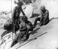 Aboriginal males sharpening rock axes on level stone. PH 416/43, ABC TV Collection, Northern Territory Library.